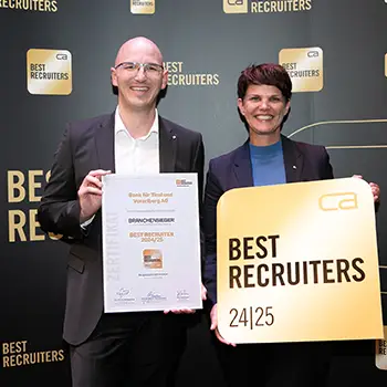 Ein Mann und eine Frau sehen lächelnd in die Kamera und halten Auszeichnungen in den Händen