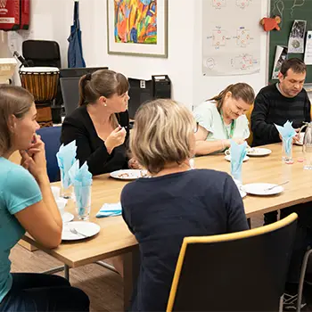 Mehrere Personen sitzen bei einem gedeckten Tisch.