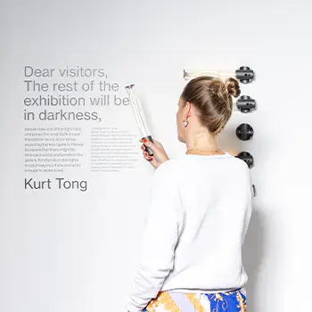 Eine Frau betrachtet eine Aufschrift auf einer Wand bei einer Ausstellung.