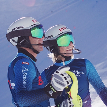 Eine Rennfahrerin hält einen Helm in den Händen, auf dem das BTV-Logo sichtbar ist.