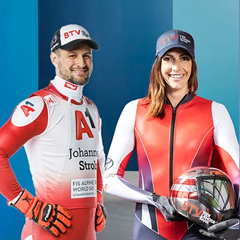 Ein Ski-Rennfahrer hält einen Helm in den Händen, auf dem das BTV-Logo sichtbar ist.